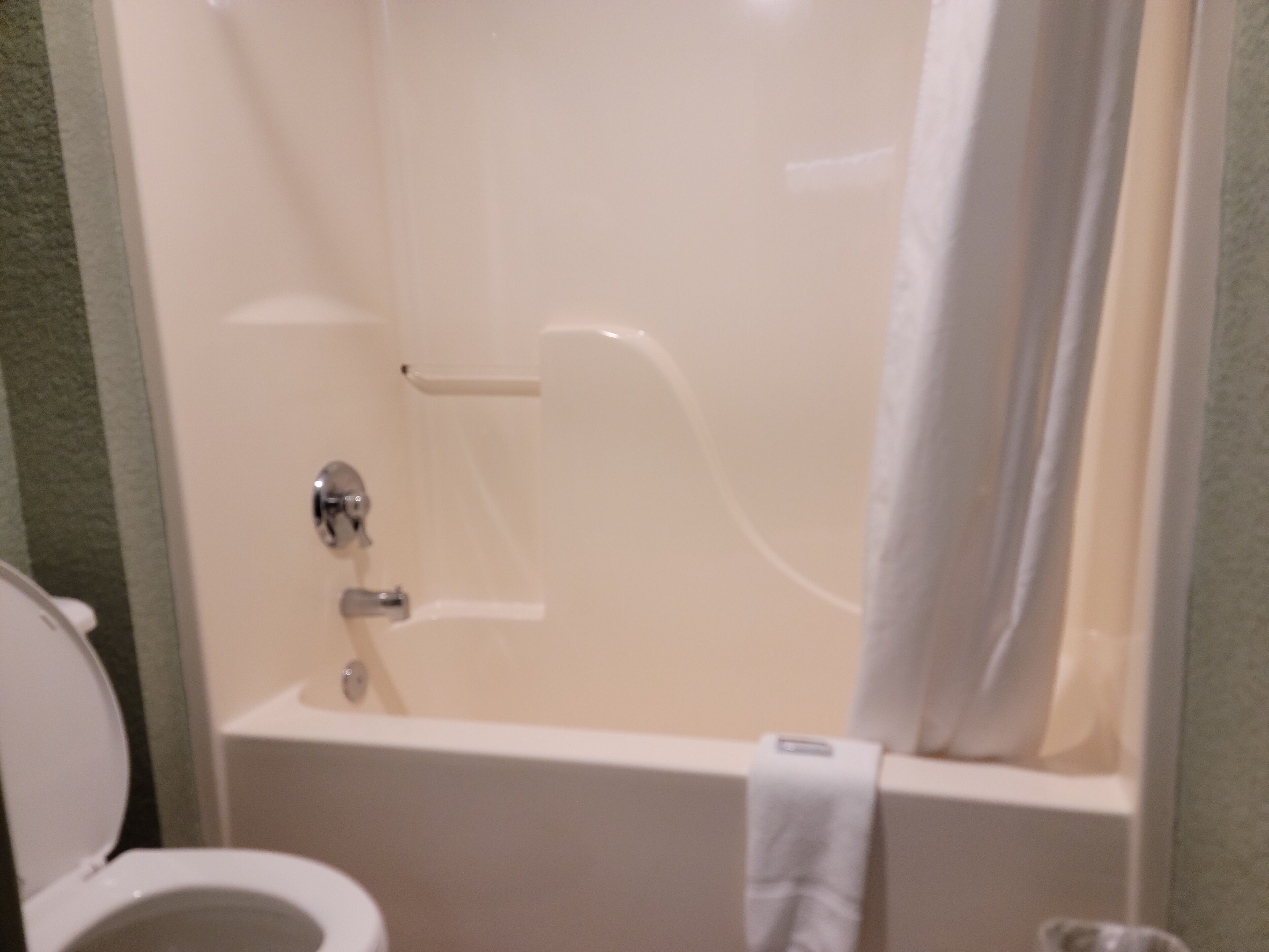 A bathroom with a bathtub, toilet, and a towel hanging on the wall.