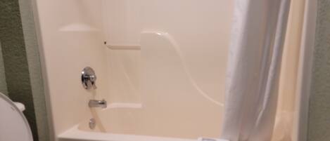 A bathroom with a bathtub, toilet, and a towel hanging on the wall.