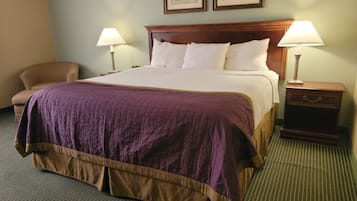 Una habitación de hotel con una cama grande, dos lámparas de noche, una mesita de madera y una silla.