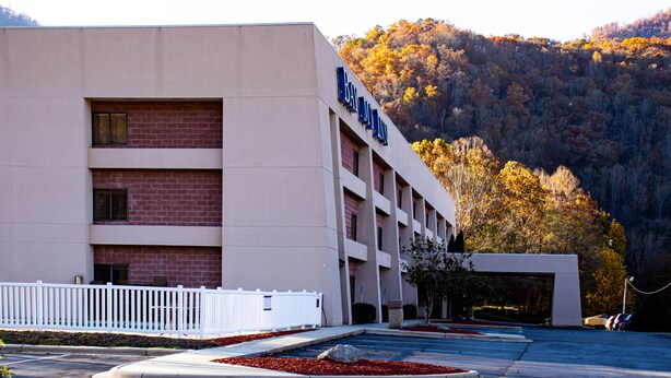 A multi-story hotel with a brick facade and a white fence in front.