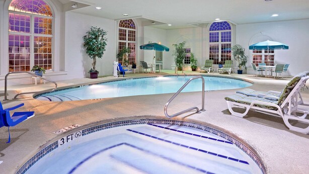 Una piscina interior con un indicador de profundidad de 90 centímetros, sillas de descanso y plantas en macetas.