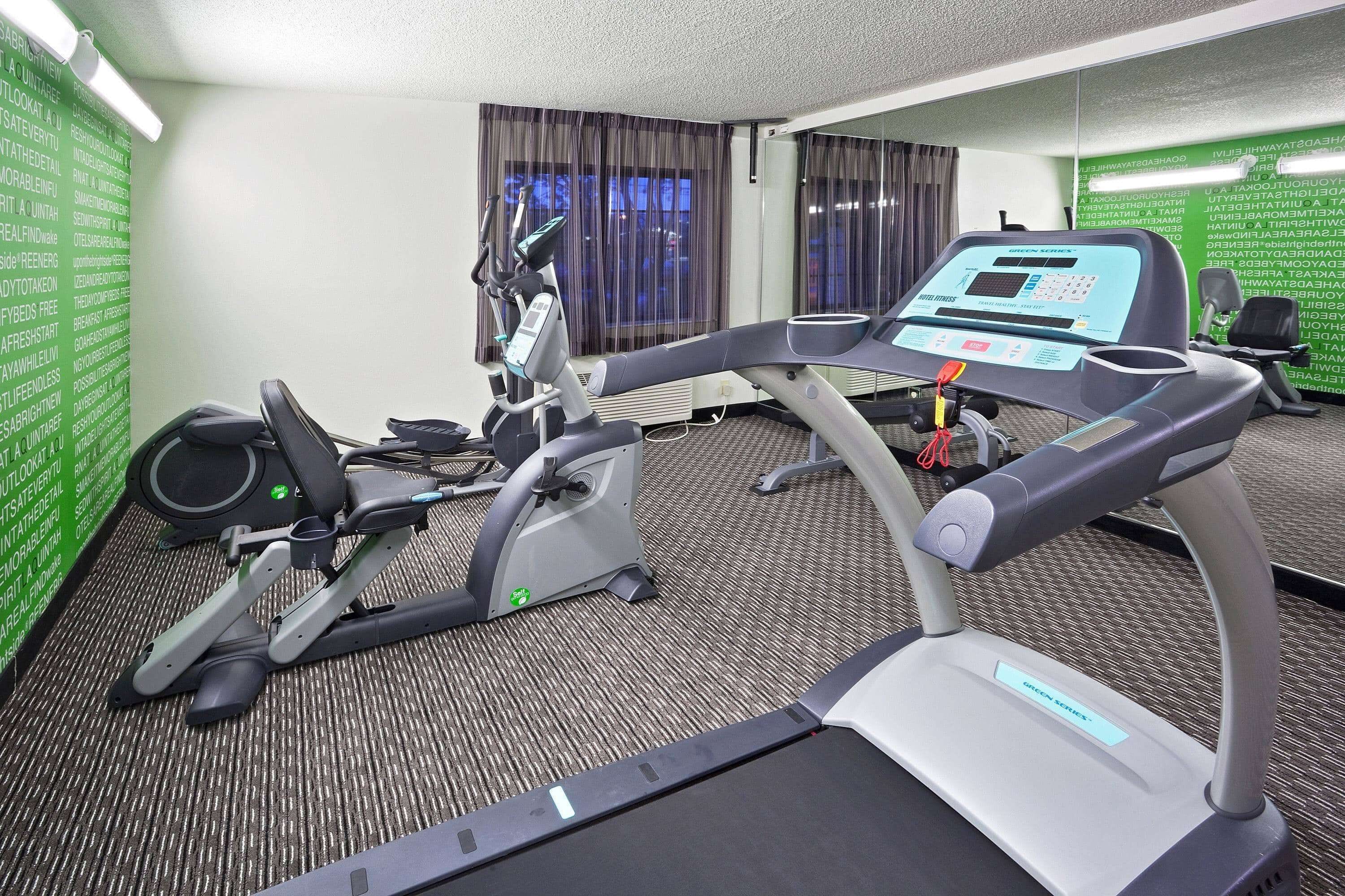 Un gimnasio de hotel con equipo de ejercicio, que incluye una cinta de correr y una bicicleta estática.