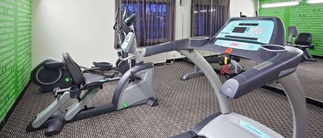 Un gimnasio de hotel con equipo de ejercicio, que incluye una cinta de correr y una bicicleta estática.