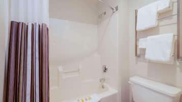 Une salle de bain avec une baignoire, des toilettes et un rideau de douche.