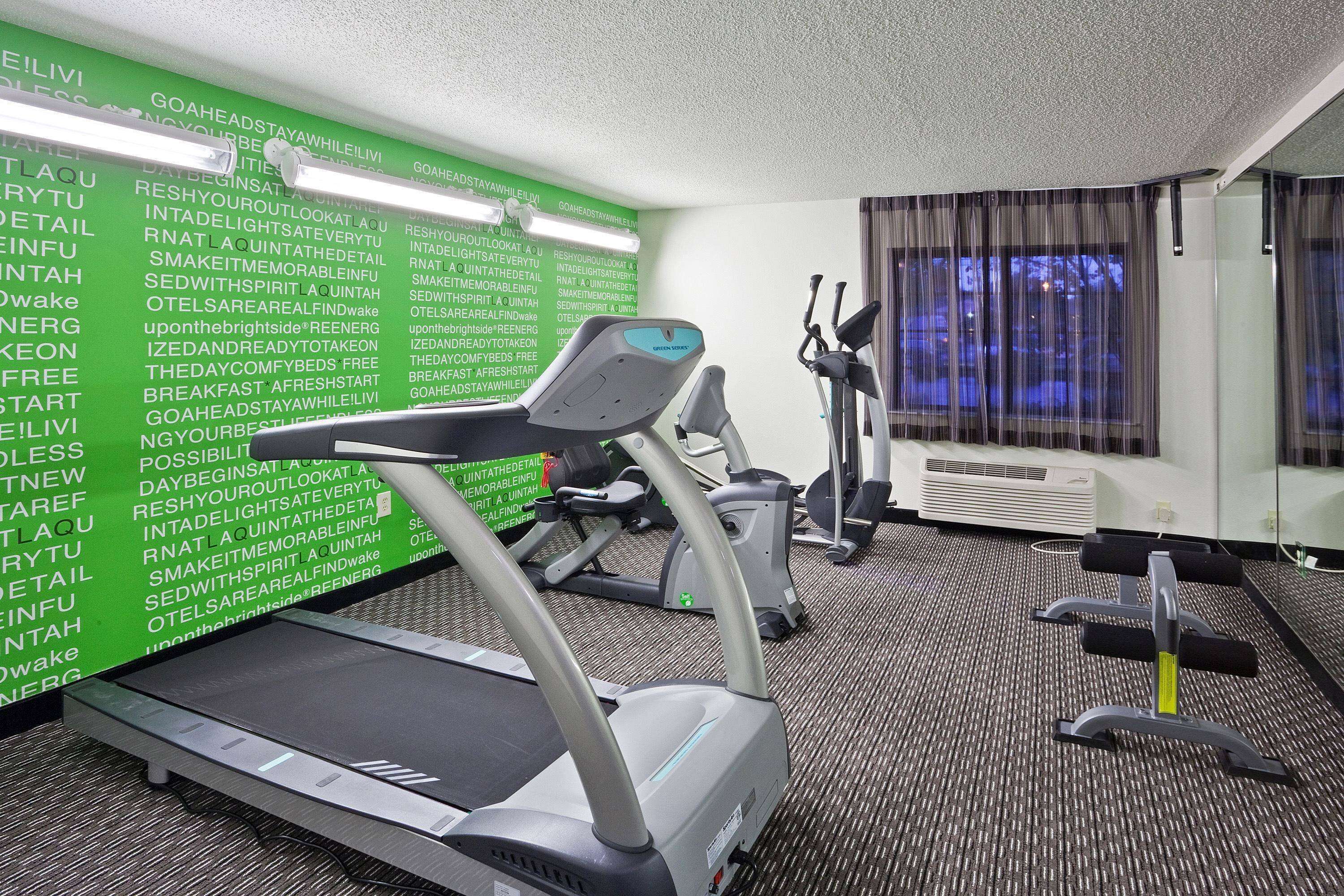 Un gimnasio de hotel con cintas de correr, bicicletas estáticas y pesas libres.
