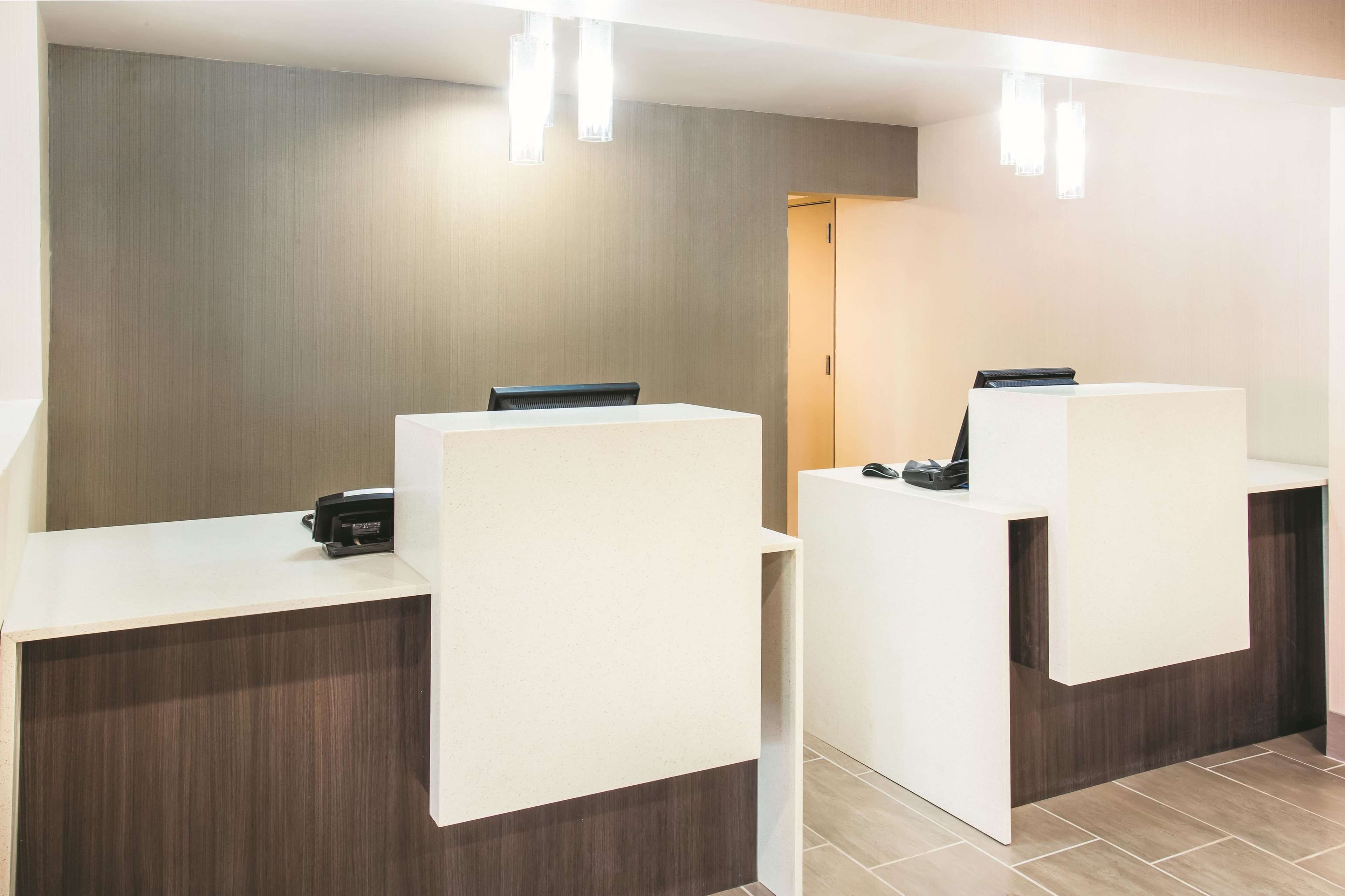A reception area with two reception desks, a wooden wall, and a door in the background.