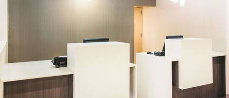 A reception area with two reception desks, a wooden wall, and a door in the background.