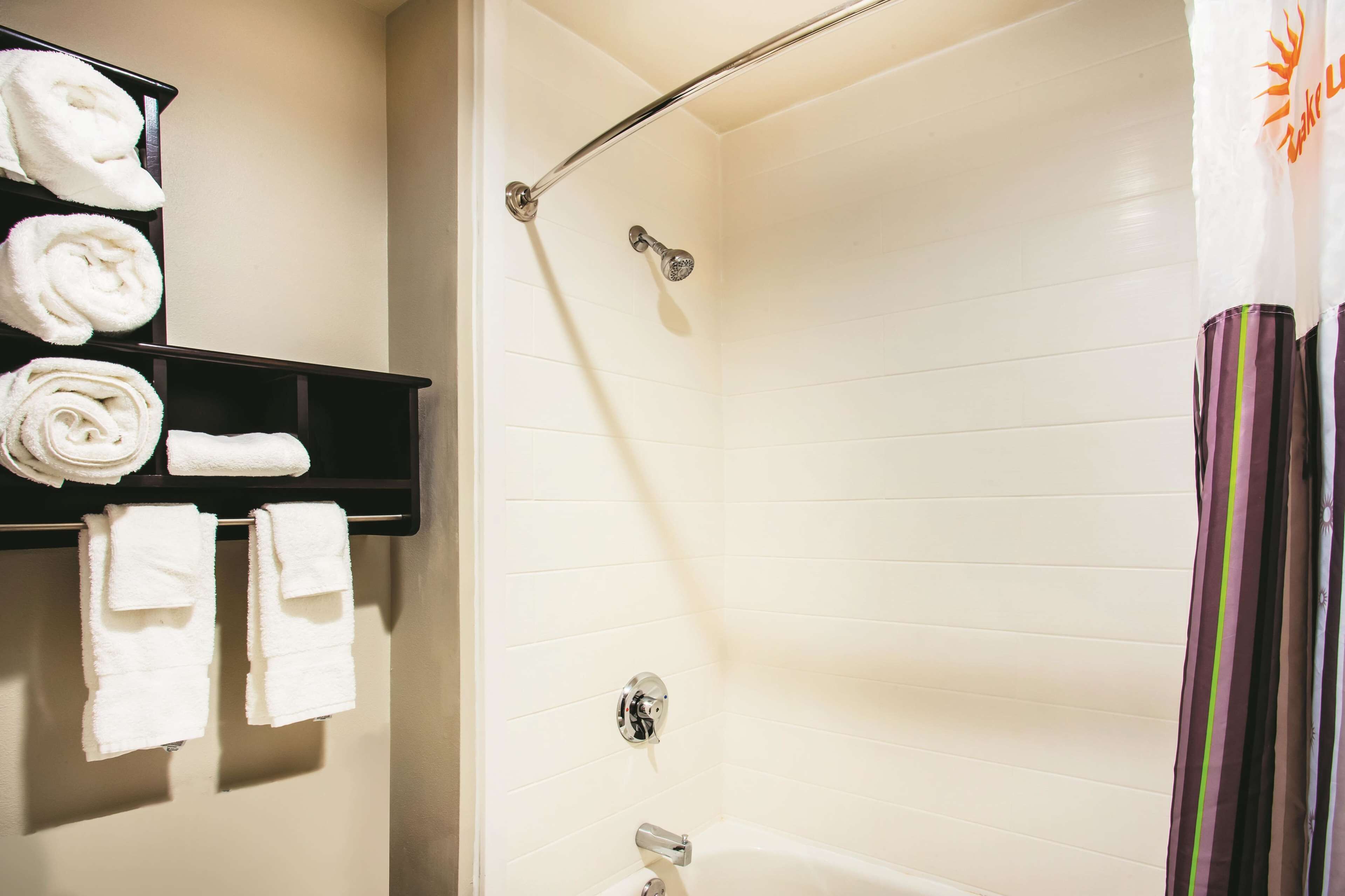 Un baño con ducha, un perchero con toallas dobladas y una cortina de baño a rayas.