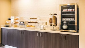A breakfast bar with pastries, a coffee machine, and a beverage dispenser. - La Quinta Inn & Suites by Wyndham Cincinnati NE - Mason (Mason)