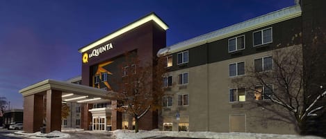 A hotel with a prominent 'La Quinta' sign, a covered entrance, and a parking lot with snow on the ground.