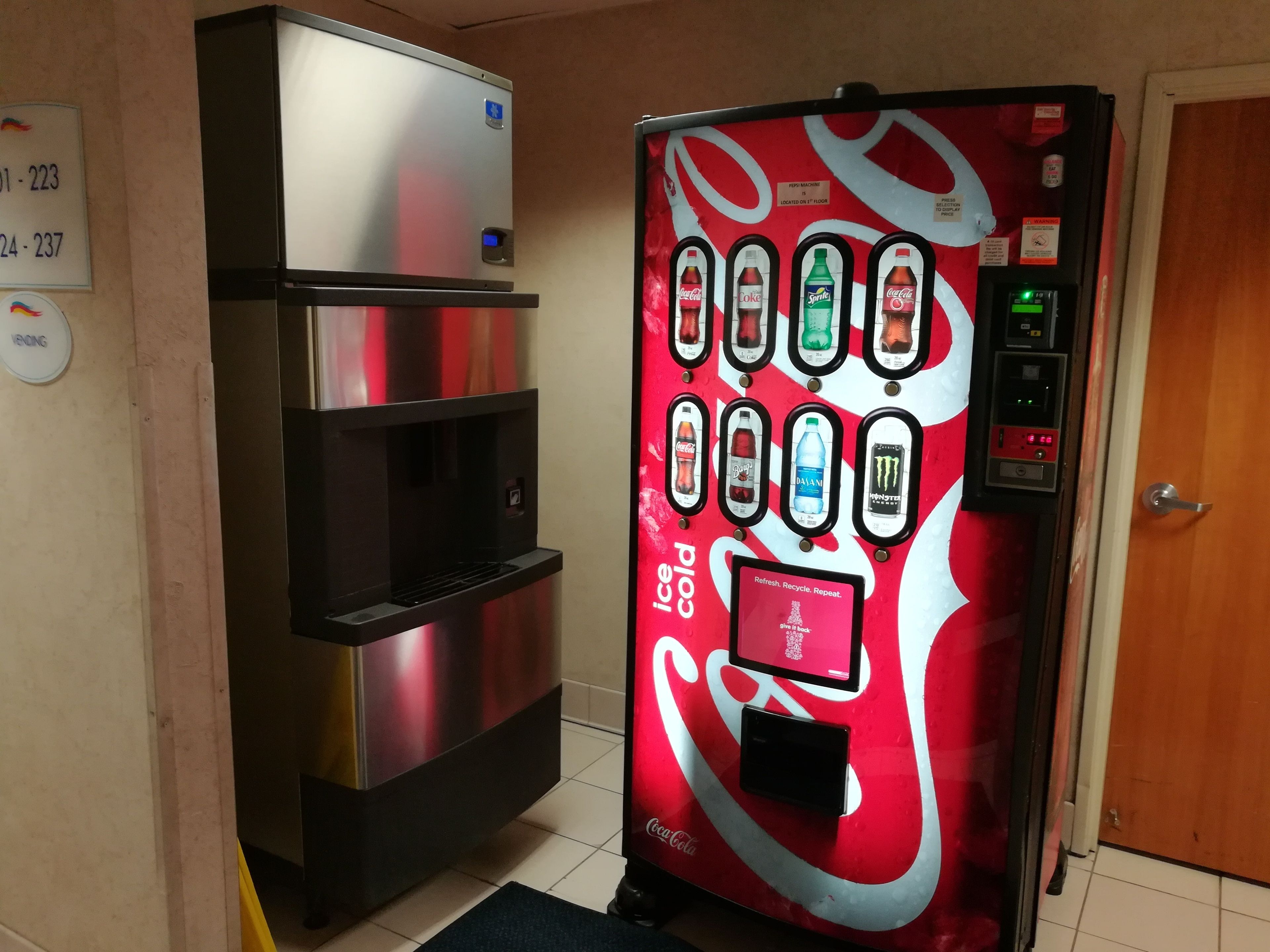 Un distributeur automatique orné du logo Coca-Cola, proposant une variété de boissons et muni d’une poubelle de recyclage.