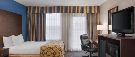 Une chambre d’hôtel avec deux lits, un bureau avec une télévision, une chaise et un four à micro-ondes.