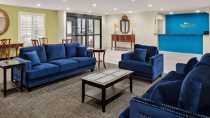 Een hotellobby met blauwe banken, een receptiebalie en een grote spiegel.