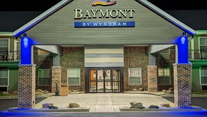 Een Baymont hotel by Wyndham met een bakstenen gevel, een opvallende ingang en blauwe accentverlichting.