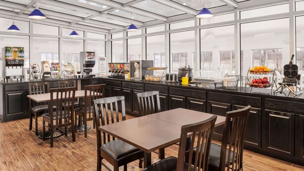 Een moderne keuken met een glazen dak, houten tafels en stoelen, en diverse keukenapparaten.