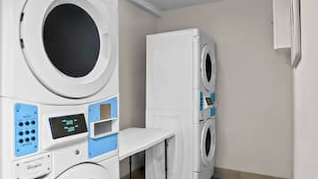 A laundry room with stacked washers and dryers, a control panel, and a table.