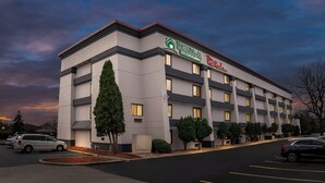 A multi-story hotel with a modern design, featuring a prominent signage for HomeTown Inn and Red Roof Inn. - HomeTowne Studios by Red Roof Flint (Flint)