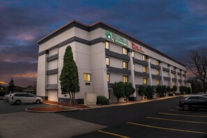 A multi-story hotel with a modern design, featuring a prominent signage for HomeTown Inn and Red Roof Inn. - HomeTowne Studios by Red Roof Flint (Flint)