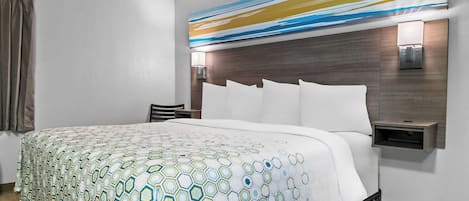 Une chambre d’hôtel avec un grand lit, une tête de lit dotée d’un luminaire, une table de chevet et une lampe fixée au mur.