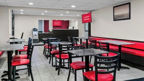 A restaurant with red and black chairs, tables, and a red counter with a digital display. - HomeTowne Studios by Red Roof Flint (Flint)