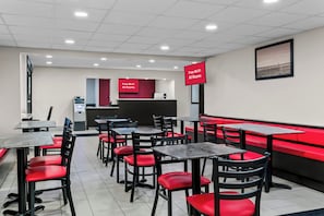 A restaurant with red and black chairs, tables, and a red counter with a digital display. - HomeTowne Studios by Red Roof Flint (Flint)