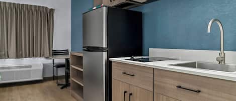 A modern kitchen with a built-in microwave, stainless steel refrigerator, and a sink with a faucet.