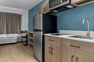 Una cocina moderna con microondas integrado, refrigerador de acero inoxidable y un lavamanos con grifo.