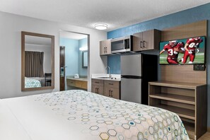 A hotel room with a bed, a TV, a microwave, and a refrigerator. - HomeTowne Studios by Red Roof Flint (Flint)