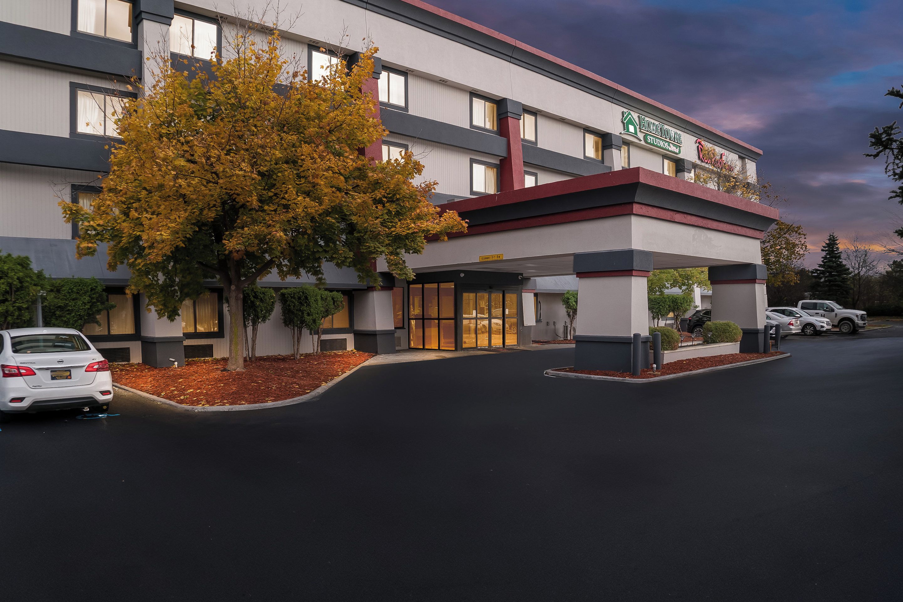 A hotel with a modern design, featuring a covered entrance and a parking area.