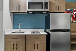 A kitchen with a microwave, refrigerator, sink, and wooden cabinets.