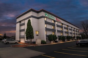 A multi-story hotel with a modern design, featuring a prominent signage for HomeTown Inn and Red Roof Inn. - HomeTowne Studios by Red Roof Flint (Flint)