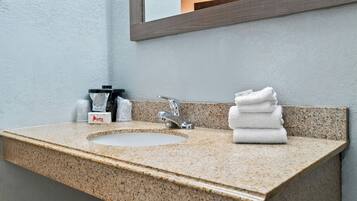 A bathroom with a granite countertop sink, a mirror, and a stack of white towels.