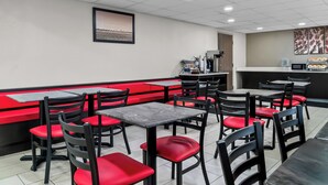A restaurant interior with booths and tables, a counter, and a framed picture on the wall. - HomeTowne Studios by Red Roof Flint (Flint)