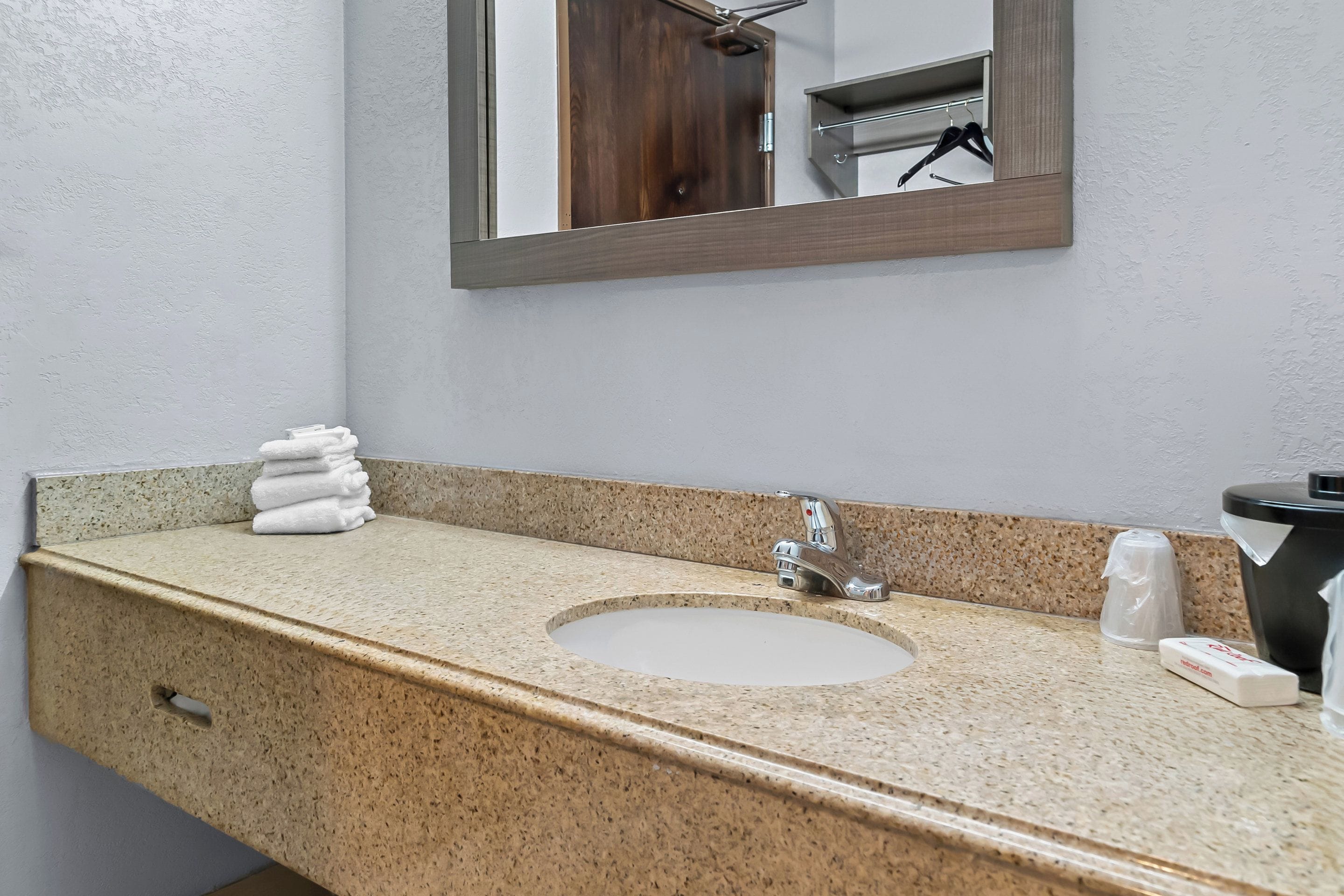 A bathroom with a granite countertop, a sink, a mirror, and a towel rack.