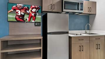 A modern kitchen with a built-in microwave, stainless steel refrigerator, and wooden cabinets.