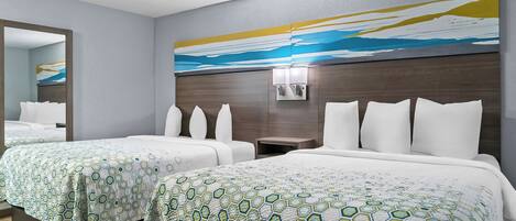 A hotel room with two beds, a large mirror, and a wall-mounted light fixture.