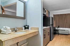 A bathroom with a sink, mirror, and towel stack. - HomeTowne Studios by Red Roof Flint (Flint)