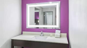 A bathroom with a white sink, purple walls, and a mirror with a white frame.