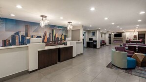 Un moderno vestíbulo de hotel con una recepción, zona de estar y un mural de la ciudad.