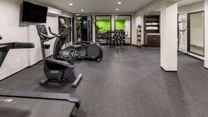 Un gimnasio con cintas de correr, elípticas y pesas libres.