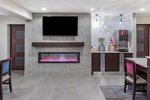 Una cocina moderna con un televisor de pantalla plana, chimenea empotrada y cafetera.