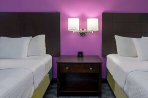 Habitación de hotel con dos camas, una mesita de noche y lámparas fijadas a la pared.