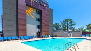 Un hotel con piscina, logotipo de sol radiante y sillones azules.