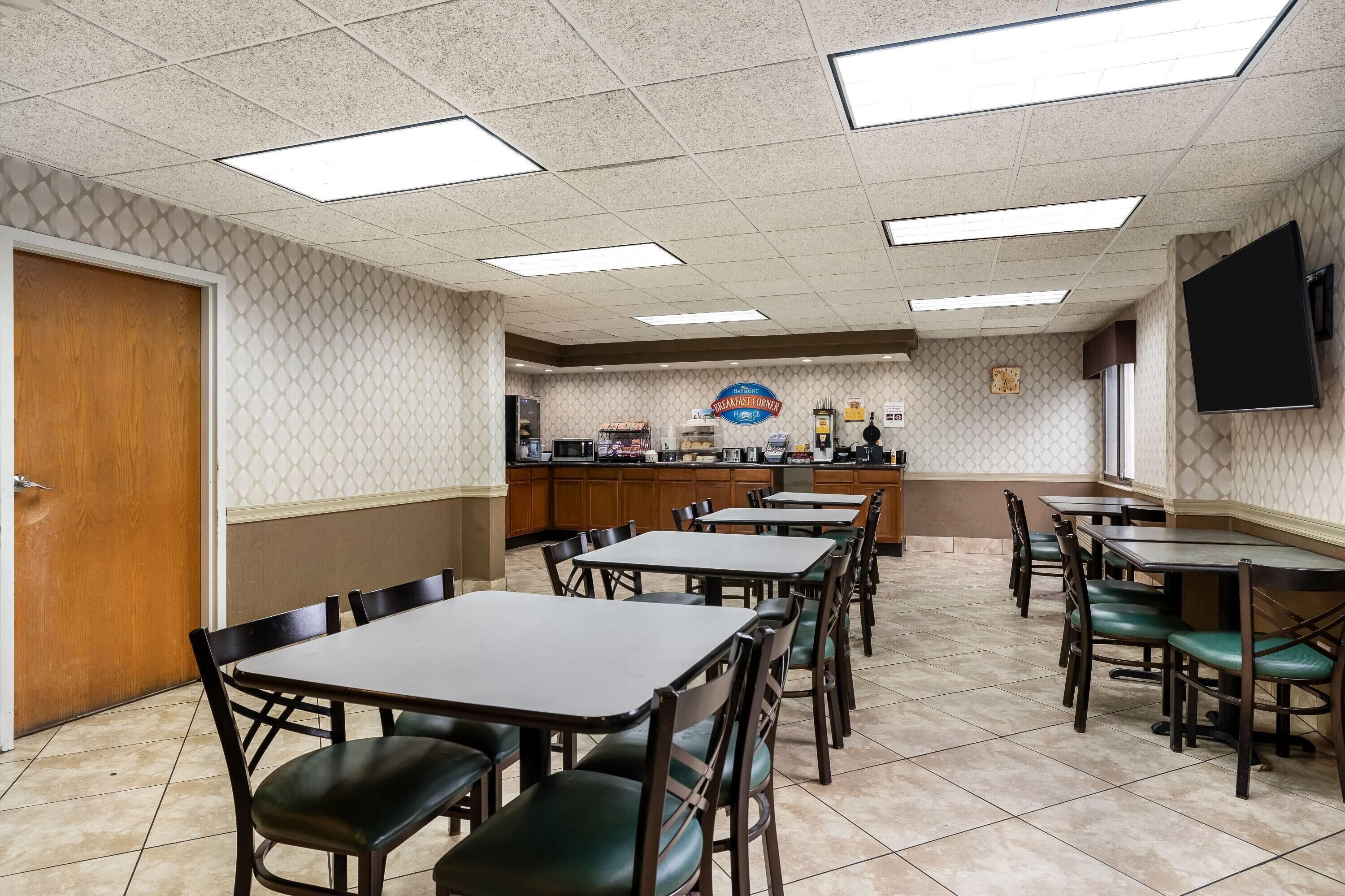 A restaurant with a counter, multiple tables, and chairs.
