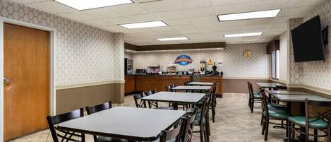 A restaurant with a counter, multiple tables, and chairs.