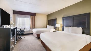 A hotel room with two beds, a desk with a chair, a television, and a window with curtains.