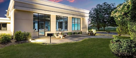 A modern building with large windows, a well-maintained lawn, and outdoor seating.