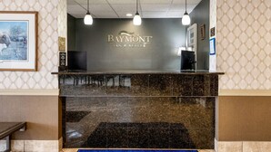 A reception desk with a 'Baymont Inn & Suites' sign, a framed picture, and a tiled wall. - Baymont by Wyndham Janesville (Janesville)