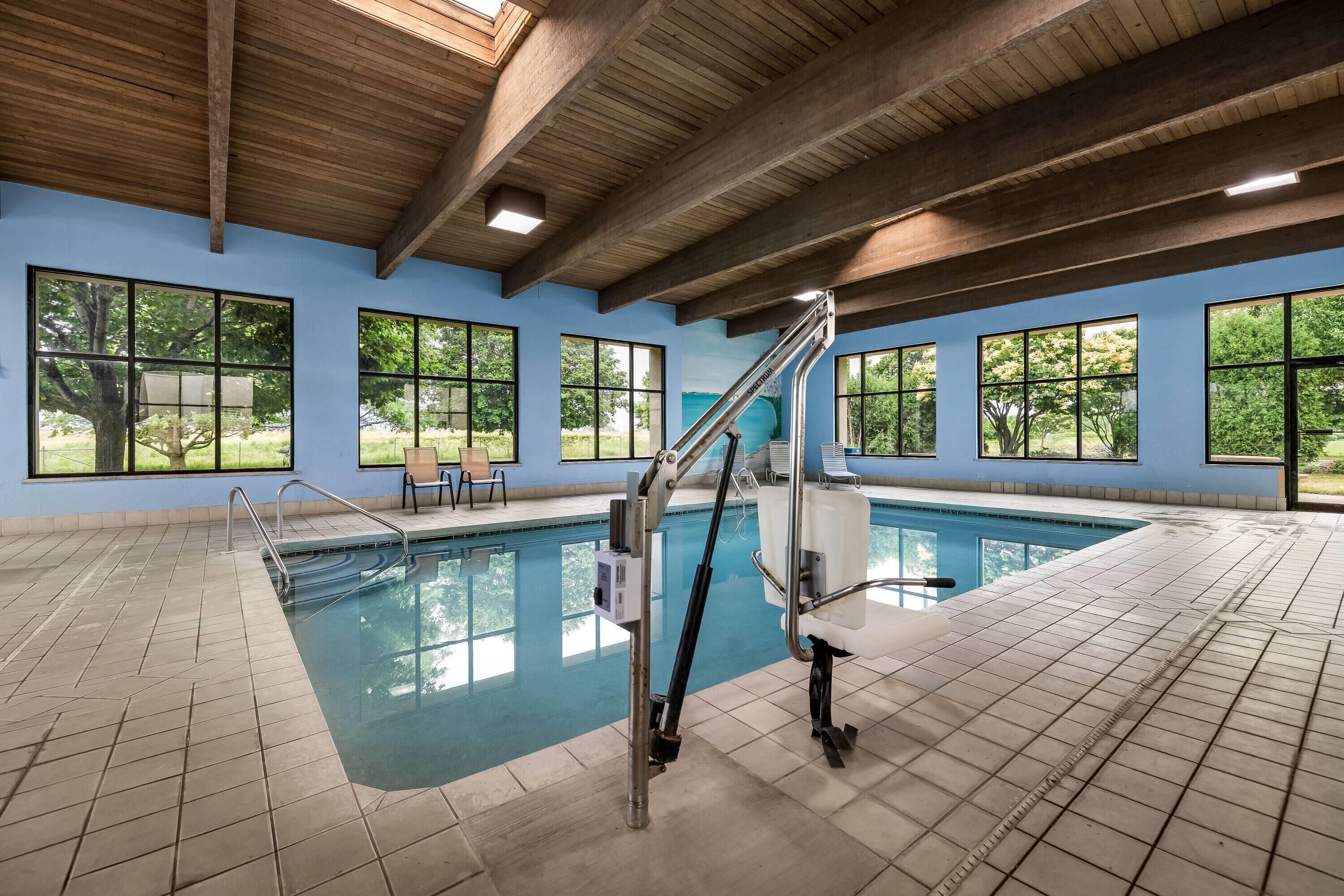 An indoor swimming pool with clear windows, a wooden ceiling, and a tiled floor.