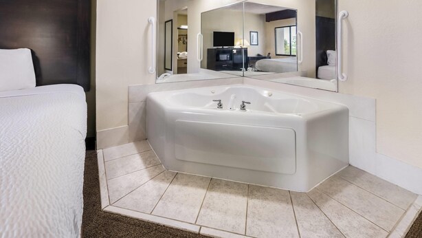 A modern bathroom with a large bathtub, a separate shower area, and a mirror above the bathtub. - Baymont by Wyndham Janesville (Janesville)